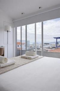 a white bedroom with two beds and a large window at ins Ígnea in Madalena