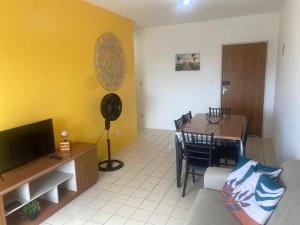 a living room with a television and a dining table at Family Beach flat - frente ao mar in Barra de São Miguel +11 photos