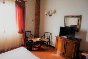 a bedroom with a bed and a tv and two chairs at Agriturismo Antico Borgo Poggitazzi in Loro Ciuffenna