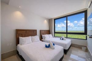 two beds in a room with a large window at Distrito Puerto by Andiani Travel in Puerto Morelos