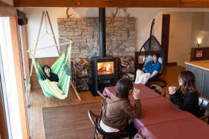 a group of people sitting in hammocks in a room with a fireplace at 白樺湖Lake View in Chino