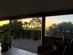 a room with a balcony with a chair and trees at Coolamon in Ballina