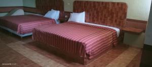two beds in a hotel room with purple sheets at Campo Real Actopan in Cedro