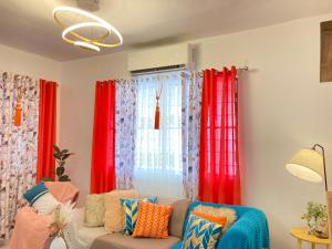 a living room with red curtains and a couch at Bahay-Kapehan sa Villa in Tambo