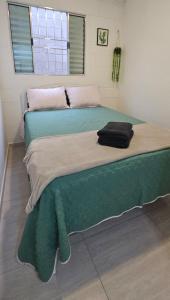 a bedroom with two beds with green sheets and a window at Casa Completa e Confortável em Cotia in Cotia