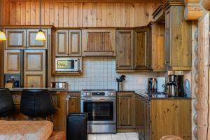 a kitchen with wooden cabinets and a stove top oven at Fiddler Lake Resort - Rabbit 66 in Mille-Isles