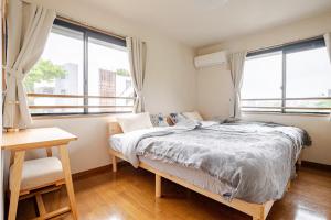 a bedroom with a bed and two large windows at B桜坂Sakurazaka APT in Susakiuramachi
