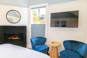 a bedroom with two blue chairs and a fireplace at BytheSea Inn in Half Moon Bay