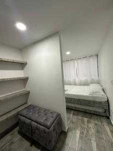 a room with a bed and a ottoman in it at Apartamento para 6, Aeropuerto, Cerca Parque del Café, Horeb Confort in La Tebaida