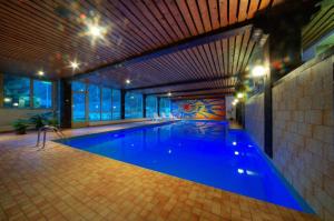 a large swimming pool with blue water in a building at Appartements Monte Rosa in Täsch