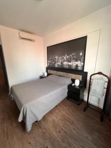 a bedroom with a bed with a large picture on the wall at Executive Flat in Apart Hotel in Campinas