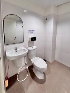 a bathroom with a white toilet and a sink at Boon Poshtel Hatyai in Sathani Hat Yai