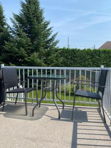 a table and two chairs sitting next to a fence at LE 710 Maison d'invitée in Saint-Georges