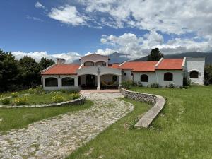 a house with a red roof on a green field at Casa Tafi del Valle in Tafí del Valle