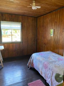 a bedroom with a bed and a ceiling fan at Merahi House Cabañas I in Hanga Roa