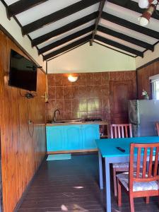 a kitchen with blue cabinets and a table and a tv at Merahi House Cabañas I in Hanga Roa