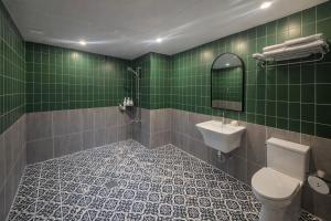 a green tiled bathroom with a toilet and a sink at Gangneung Wheel Hotel in Gangneung +31 photos