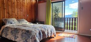 a bedroom with a bed and a large window at casa caburgua en cerro in Caburgua
