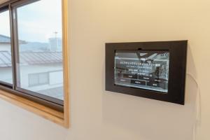 a television on a wall next to a window at まちやど半歩 in Shimo-suwa