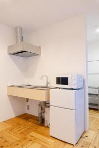 a white kitchen with a sink and a microwave at まちやど半歩 in Shimo-suwa +4 photos