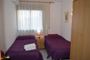 2 łóżka w pokoju z fioletową pościelą i oknem w obiekcie Villa Lagem w Cubelles