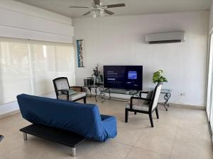 a living room with a blue couch and chairs and a tv at Beach House in Coronado in Nueva Gorgona