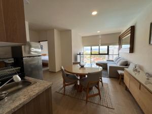 a kitchen and living room with a table and a couch at Gran departamento con alberca, terraza y vista a lago en Lago Luna - 5 minutos de Chante Spa in Chantepec