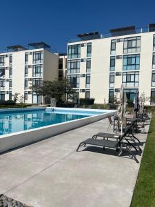 a swimming pool in front of a building at Gran departamento con alberca, terraza y vista a lago en Lago Luna - 5 minutos de Chante Spa in Chantepec