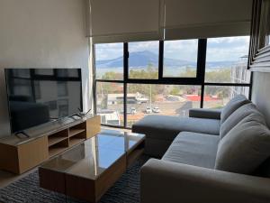 a living room with a couch and a flat screen tv at Gran departamento con alberca, terraza y vista a lago en Lago Luna - 5 minutos de Chante Spa in Chantepec