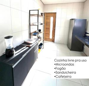 a kitchen with a stainless steel refrigerator and white tiled walls at Mini Suite - Pousada Lemon com Cozinha - Sesc Bertioga - Ar Condicionado e Frigobar in Bertioga