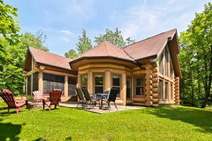 a log cabin with a table and chairs in the yard at Fiddler Lake Resort - Rabbit 12 in Mille-Isles