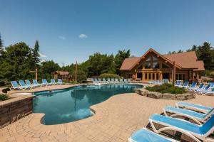 a pool with lounge chairs and a log cabin at Fiddler Lake Resort - Rabbit 12 in Mille-Isles