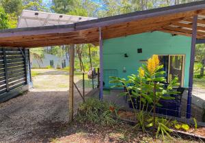 a green house with a wooden pergola at Lakeside 3-BR Forest Cottage in Laurieton +19 photos