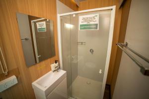 a bathroom with a shower and a toilet and a sink at Gunyah by Tiny Away in Mount McDonald