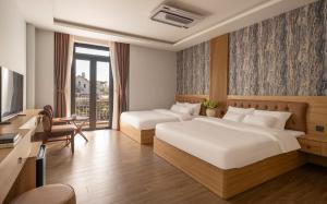 a hotel room with two beds and a television at Khách sạn Brume Đà Lạt in Da Lat