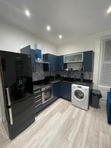 a kitchen with blue cabinets and a washing machine at Stylish 2BR Duplex - Central & Spacious in Sunderland