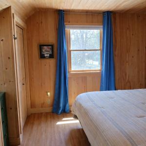 a bedroom with a bed and a window with blue curtains at Cozy Coastal Hideaway with Harbor Views in Tremont +3 photos