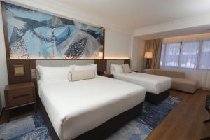 a hotel room with two beds and a couch at Perdana Kota Bharu in Kota Bharu