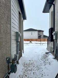 a snow covered alley with a building and a parking meter at Spacious and Stylish Private Basement Suite - 1 bed and 1 rec room in Winnipeg