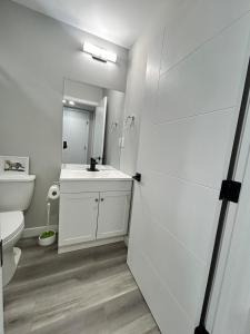 a white bathroom with a sink and a toilet at Spacious and Stylish Private Basement Suite - 1 bed and 1 rec room in Winnipeg +17 photos