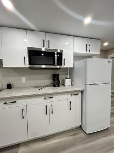 a kitchen with white cabinets and a microwave at Spacious and Stylish Private Basement Suite - 1 bed and 1 rec room in Winnipeg