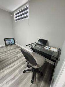 a desk with a laptop and a chair in a room at Spacious and Stylish Private Basement Suite - 1 bed and 1 rec room in Winnipeg