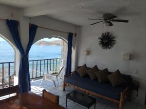 a living room with a couch and a view of the ocean at Bungalow Encanto in Zihuatanejo