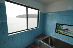 ein Badezimmer mit Badewanne und Blick aufs Wasser in der Unterkunft あわい in Kure