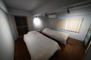 zwei Betten in einem kleinen Zimmer mit Fenster in der Unterkunft あわい in Kure