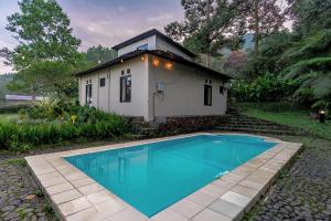a small house with a blue pool in front of it at Lingga Garden House in Puncak