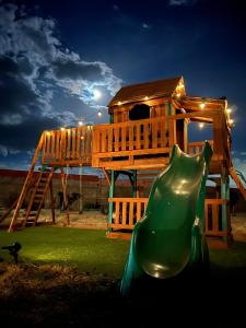 a tree house with a green slide and a house at Cabaña con Piscina para Descansar in Chihuahua