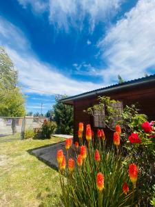 a garden with red flowers in front of a house at CABAÑA Nuestra Señora de Luján in Perito Moreno
