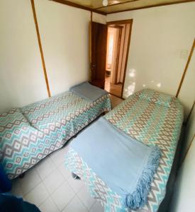 a room with two beds in a room with a doorway at CABAÑA Nuestra Señora de Luján in Perito Moreno