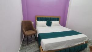 a small bedroom with a bed and a chair at Hotel Dharma palace in Prayagraj